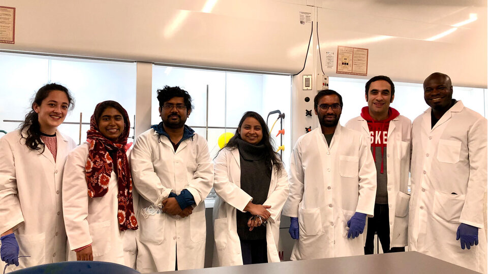Seven people in lab coats standing in a row